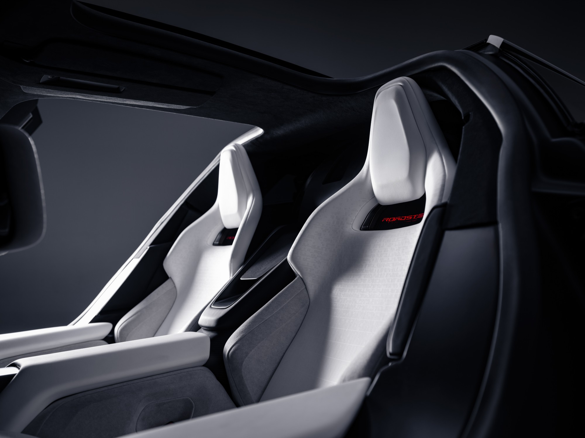 The Roadster’s two white sports seats under an open roof, with the Roadster name stitched in red on the headrest